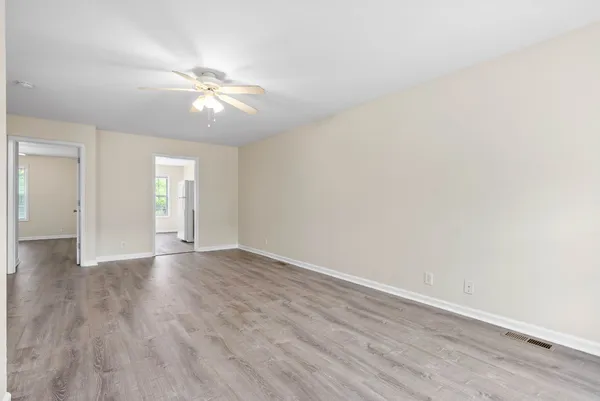 a view of an empty room with wooden floor and window