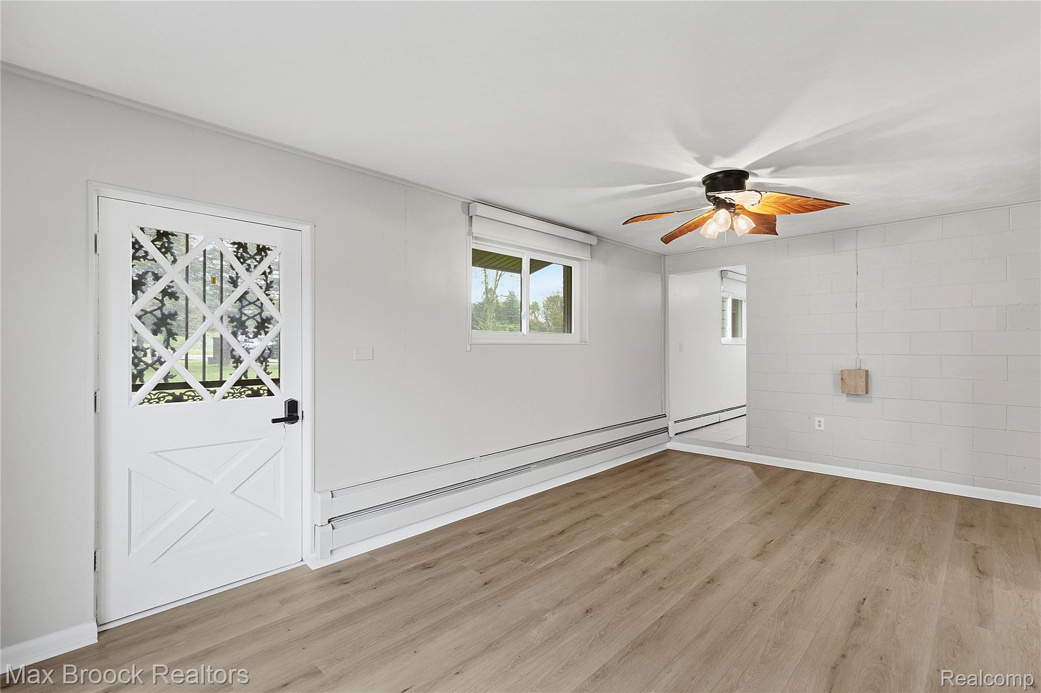 1392 Maple Grove Road Lapeer, MI 48446 - Photo 12 of 70 Spare room featuring ceiling fan, light wood-style flooring, a baseboard heating unit, and concrete block wall