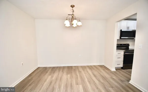 a view of kitchen and empty room with wooden floor