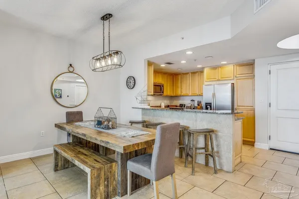 a kitchen with stainless steel appliances granite countertop a sink a stove cabinets dining table and chairs