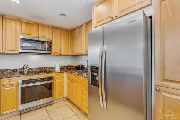 a kitchen with granite countertop white cabinets stainless steel appliances and a counter space