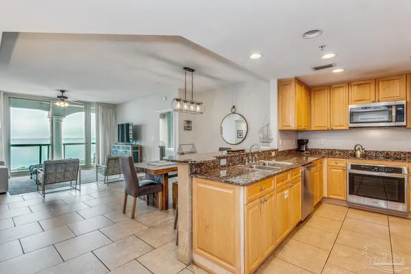 a kitchen with stainless steel appliances granite countertop a stove top oven a sink dishwasher a dining table and chairs with wooden floor