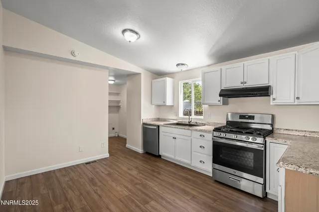 a kitchen with granite countertop a stove top oven and cabinets