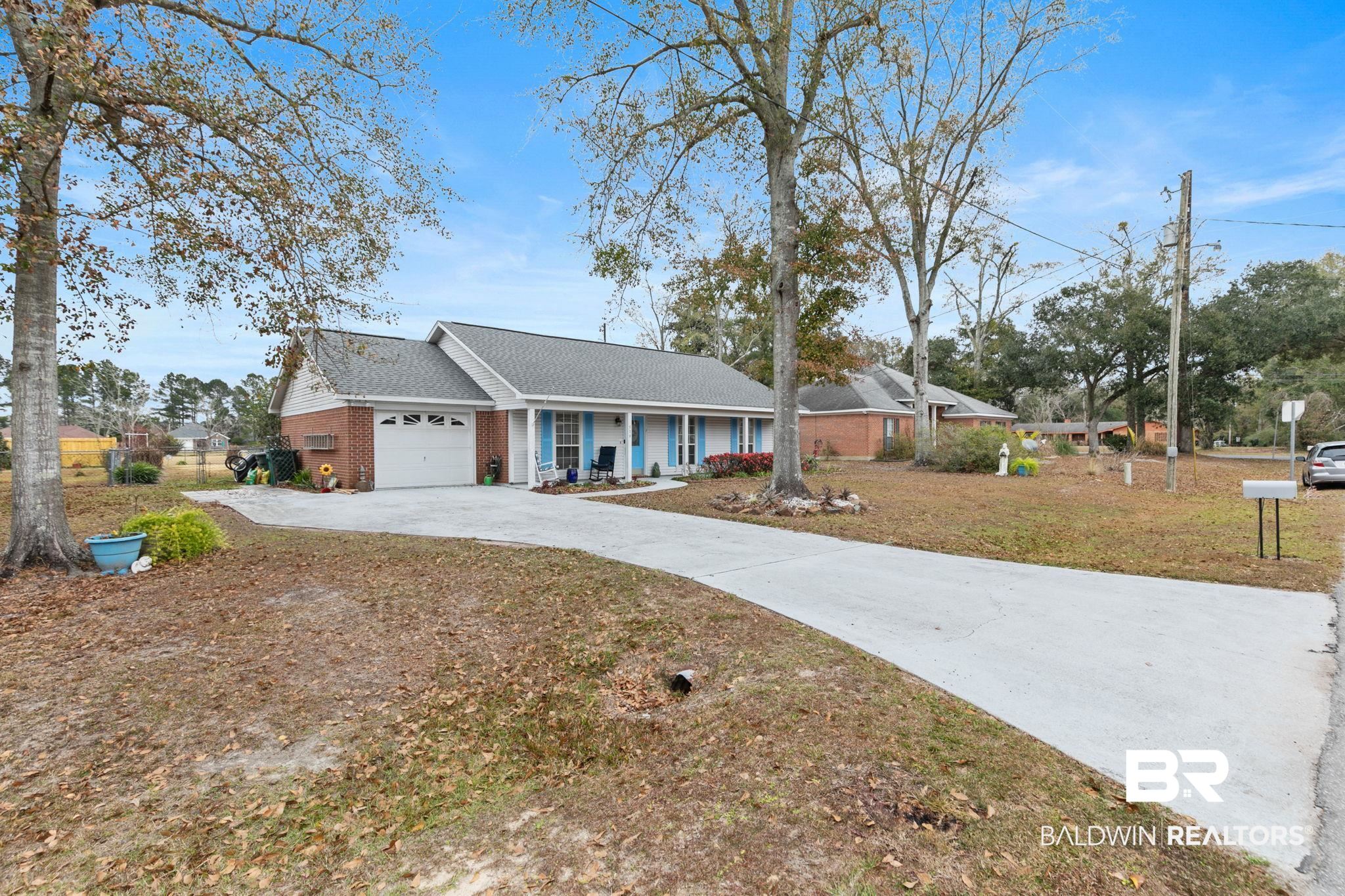 519 Juniper Place Drive Foley, AL 36535 - Photo 2 of 47 Single story home featuring a shingled roof, driveway, a garage, brick siding, and covered porch