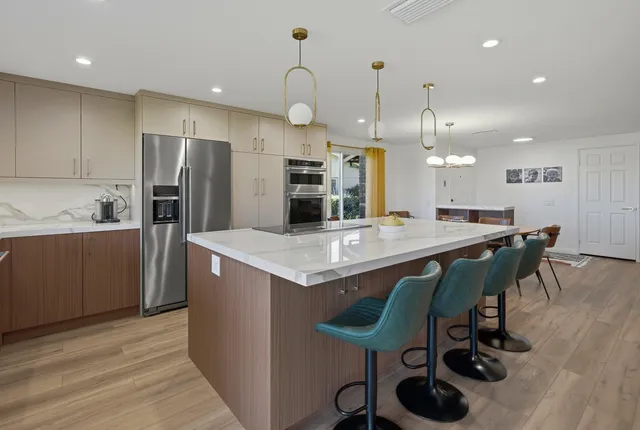 a kitchen with kitchen island a dining table wooden floor and stainless steel appliances