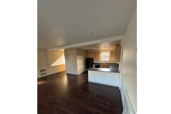 a view of a living room with kitchen and wooden floor