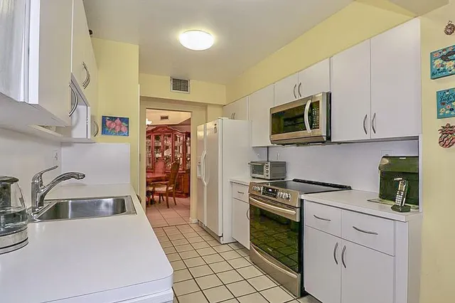 a kitchen with stainless steel appliances granite countertop a sink a stove oven and white cabinets