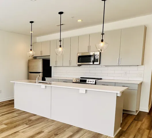 a kitchen with stainless steel appliances kitchen island a white cabinets and a wooden floor