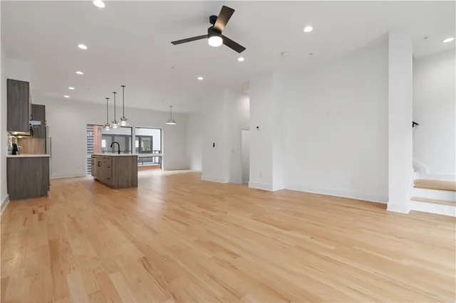 a big room with wooden floor and kitchen view