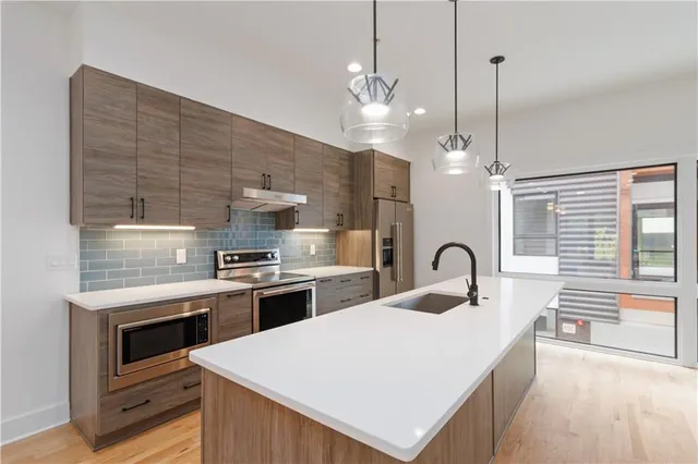 a kitchen with a stove a sink a kitchen island with wooden cabinets and floor