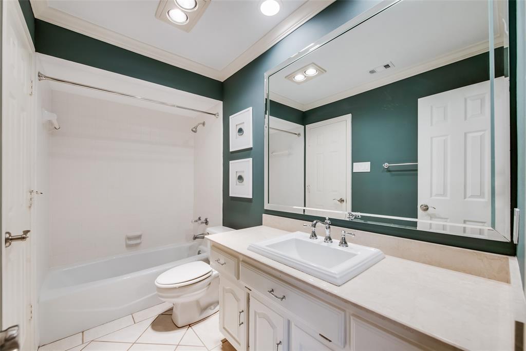 15720 Golden Creek Road Dallas, TX 75248 - Photo 14 of 25 The bathroom features a vanity with an integrated sink, a rectangular mirror, and a bathtub with a shower