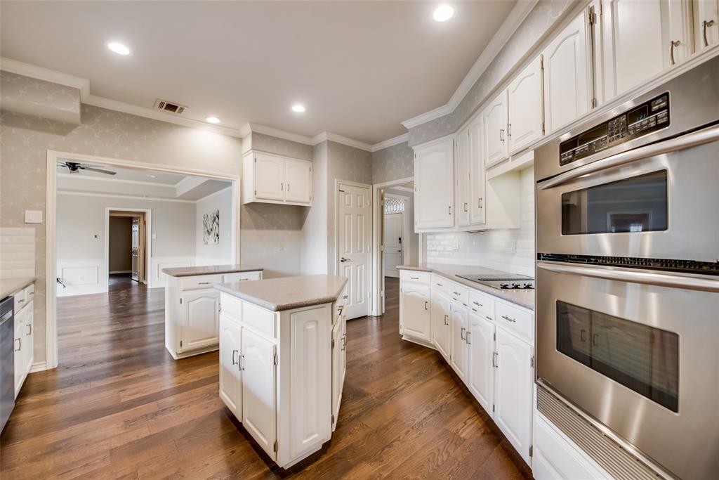 15720 Golden Creek Road Dallas, TX 75248 - Photo 2 of 25 The kitchen features hardwood floors, white cabinetry, and stainless steel built-in appliances, including a double oven