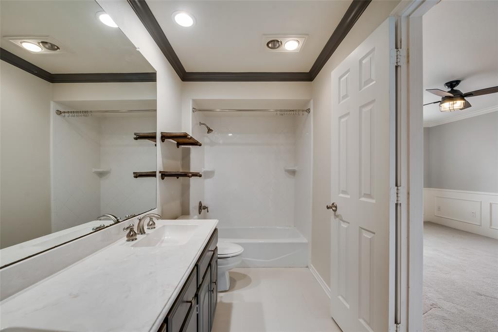 15720 Golden Creek Road Dallas, TX 75248 - Photo 21 of 25 This bathroom features a spacious vanity with an integrated sink and an expansive mirror