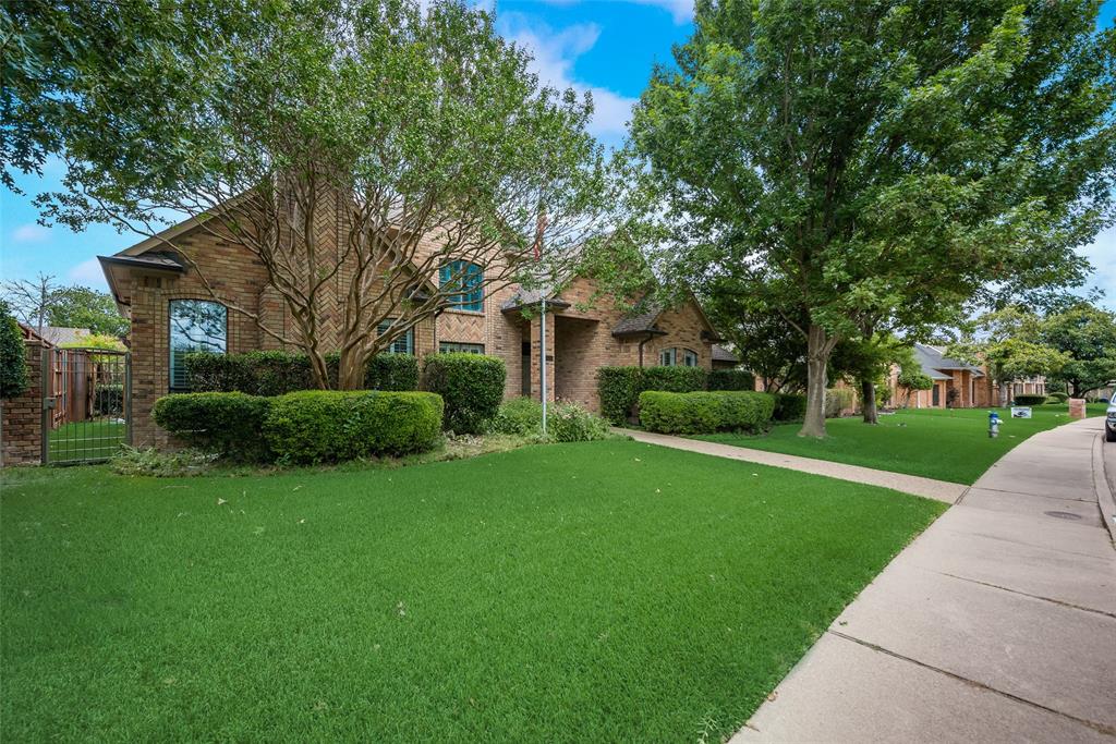 15720 Golden Creek Road Dallas, TX 75248 - Photo 25 of 25 The property features a brick exterior, a well-maintained lawn, and mature trees