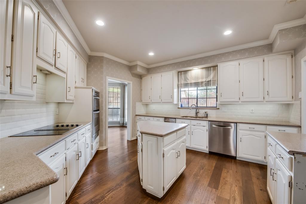 15720 Golden Creek Road Dallas, TX 75248 - Photo 3 of 25 The kitchen features hardwood floors, white cabinetry, and granite countertops