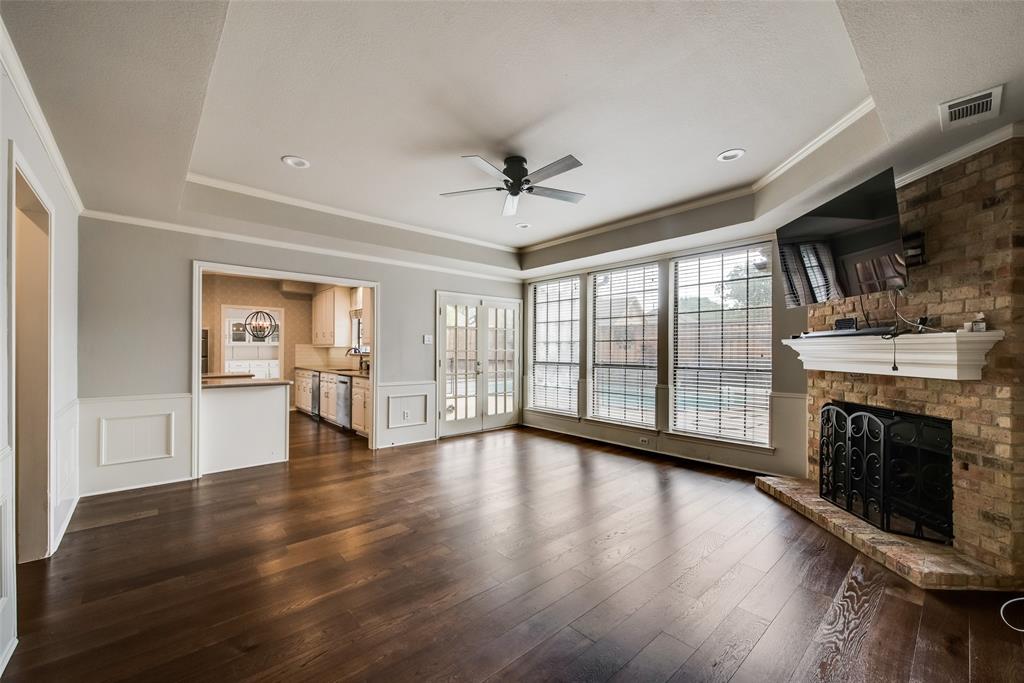 15720 Golden Creek Road Dallas, TX 75248 - Photo 6 of 25 This spacious living area features dark wood flooring, a brick fireplace with a white mantel, and crown molding