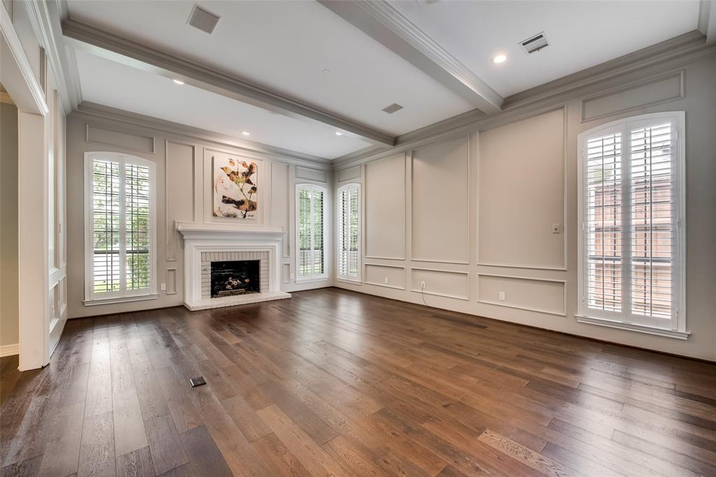 15720 Golden Creek Road Dallas, TX 75248 - Photo 9 of 25 Spacious room featuring rich hardwood floors, a white brick fireplace with a decorative mantel, and tall arched windows with white plantation shutters