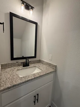 a bathroom with a granite countertop sink and mirror