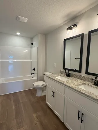 a bathroom with a granite countertop sink mirror and a toilet