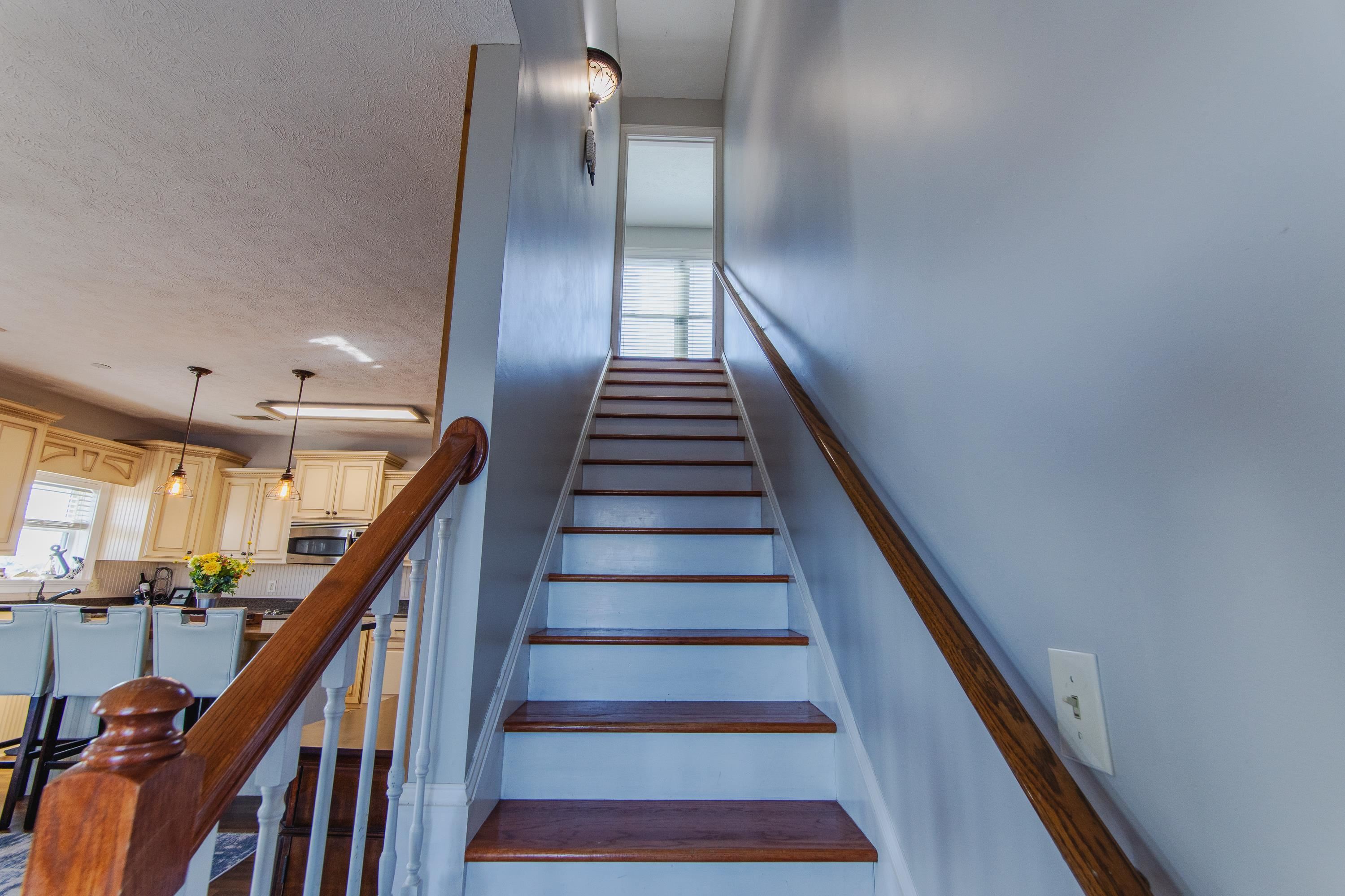 1111 Leaning Trees Lane Adamsville, TN 38310 - Photo 15 of 36 Two-tone staircase featuring wood-finish treads and white risers, complemented by a wood-finish handrail and newel post