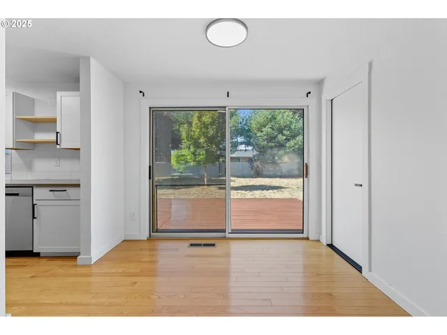 a view of an empty room with a window and wooden floor