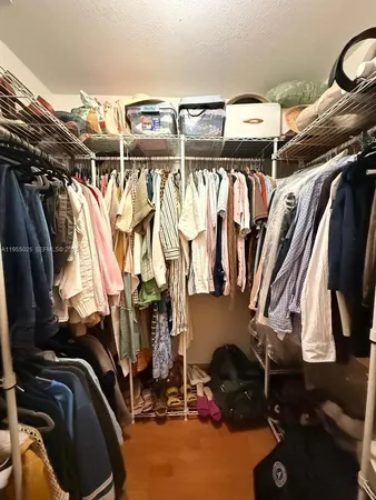 a view of walk in closet with clothes and shoes