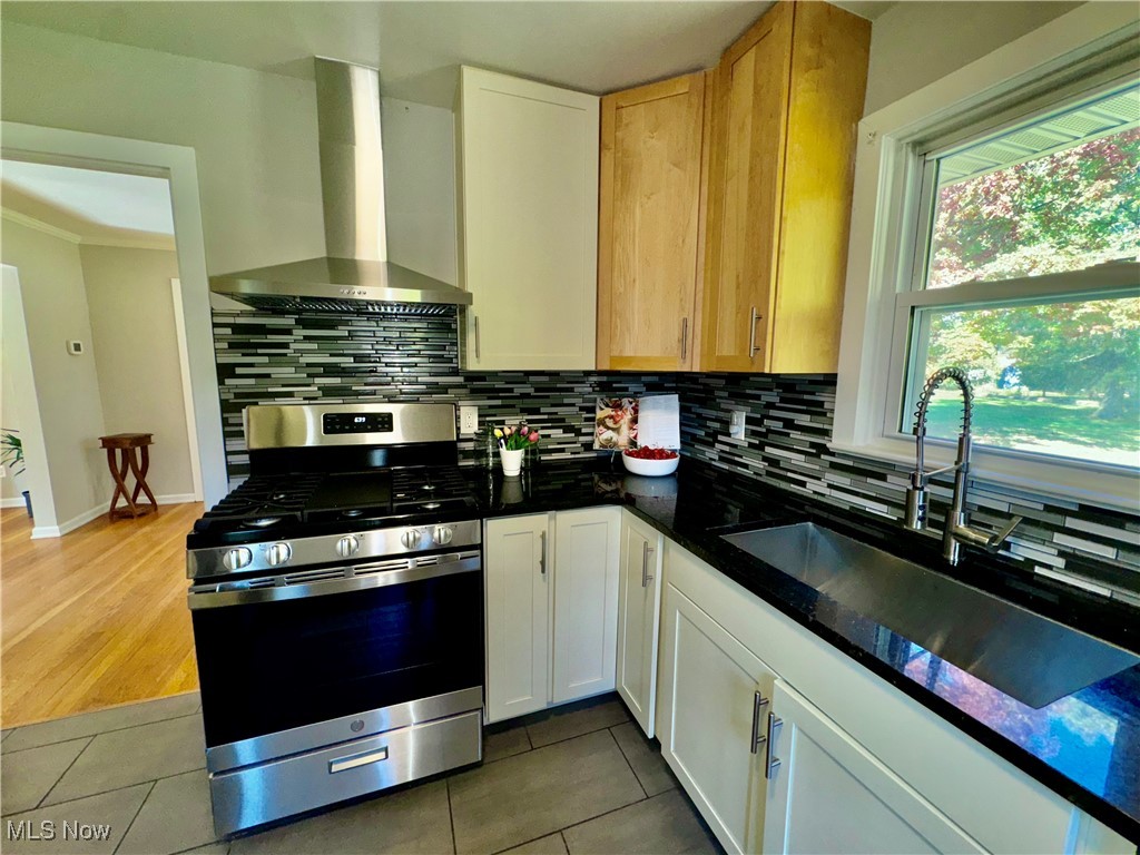 1729 East Pleasant Valley Road Independence, OH 44131 - Photo 16 of 41 Kitchen with stainless steel range with gas stovetop, tasteful backsplash, wall chimney exhaust hood, and white cabinetry