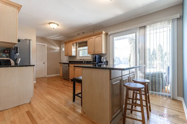 a kitchen with stainless steel appliances granite countertop a stove a sink a refrigerator and white cabinets with wooden floor