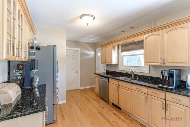 a kitchen with stainless steel appliances granite countertop a refrigerator a sink dishwasher a stove with wooden cabinets and floor