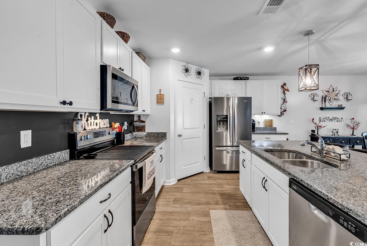 164 Seasons Trace Loop Longs, SC 29568 - Photo 7 of 40 Kitchen with appliances with stainless steel finishes, white cabinetry, dark stone counters, hanging light fixtures, and light wood-style floors