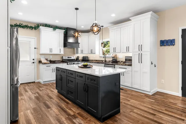 a kitchen with stainless steel appliances granite countertop a sink a stove a refrigerator and a oven with wooden floor