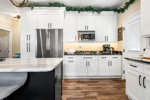 a kitchen with stainless steel appliances granite countertop a sink dishwasher a stove and white cabinets with wooden floor