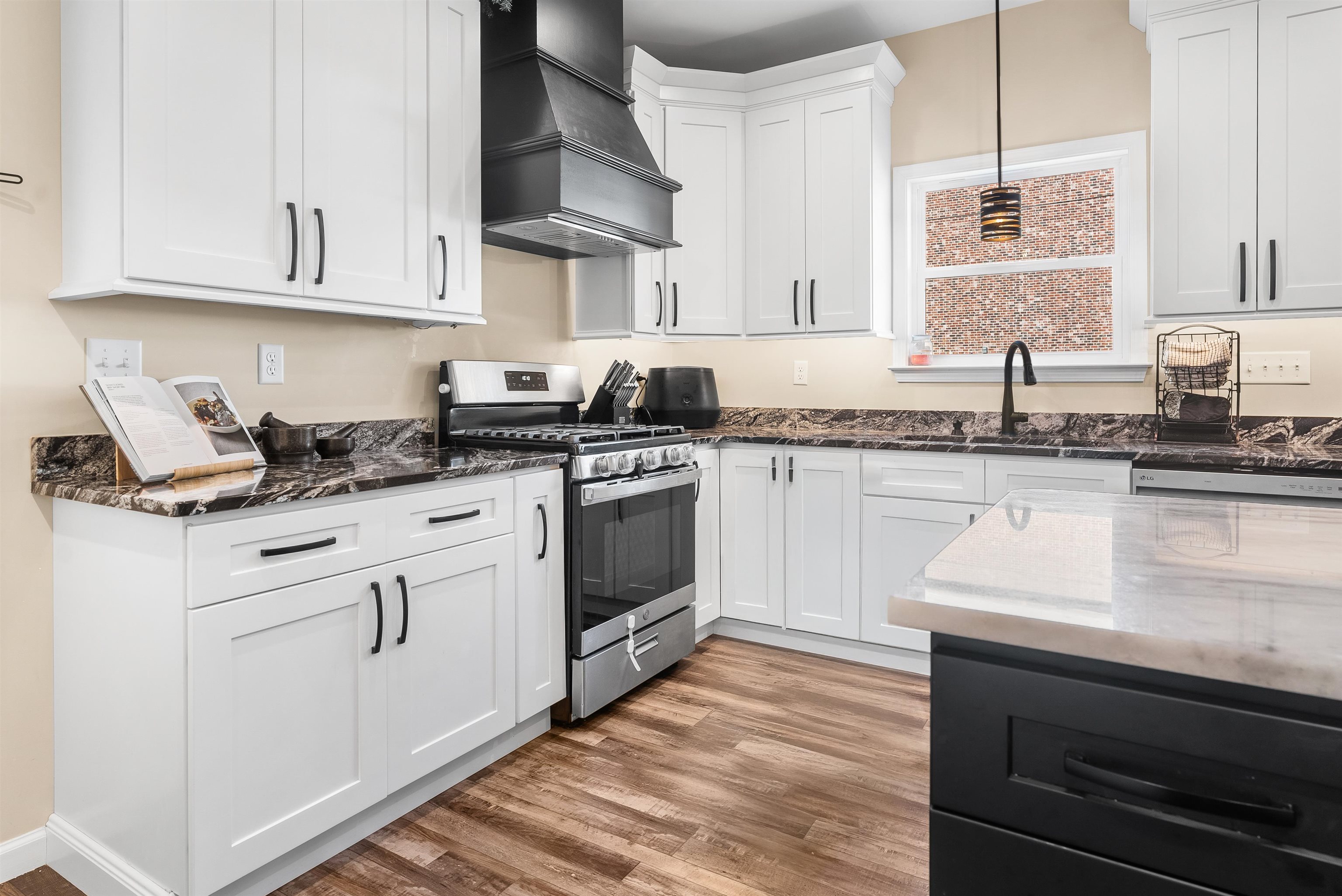 212 South Tipton Street Covington, TN 38019 - Photo 7 of 27 a kitchen with stainless steel appliances granite countertop a sink dishwasher a stove and white cabinets with wooden floor