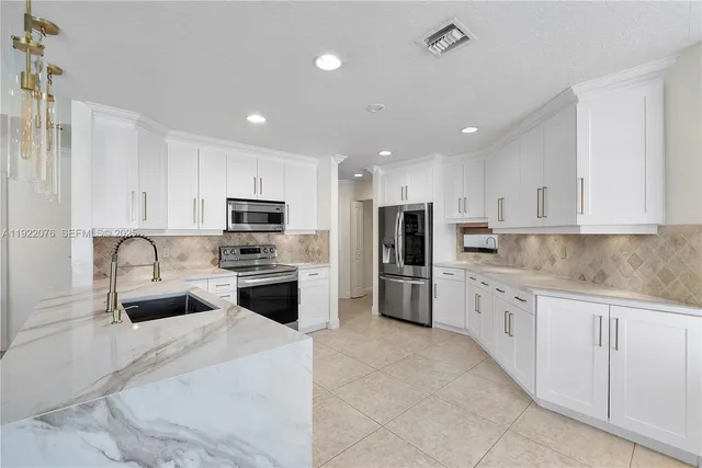 a kitchen with granite countertop white cabinets and stainless steel appliances
