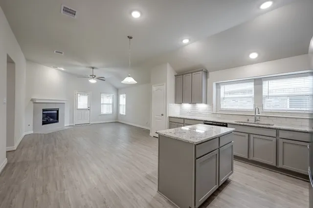 a kitchen with granite countertop a sink window and cabinets