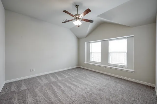 an empty room with ceiling fan and window