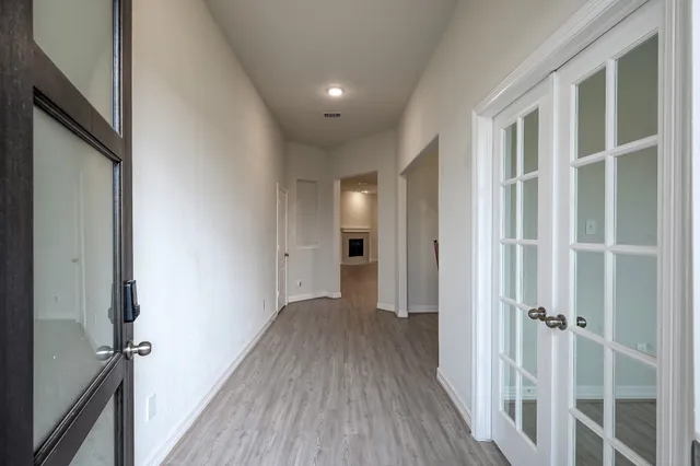 a view of a hallway with wooden floor and a bathroom