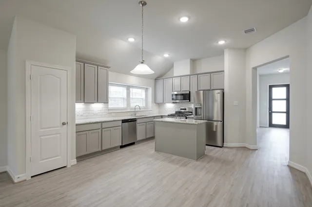 a kitchen with a refrigerator sink and cabinets