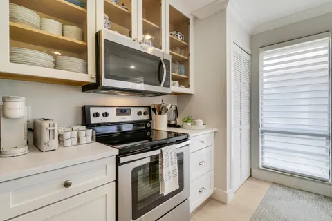 a kitchen with stainless steel appliances granite countertop white cabinets and a stove top oven