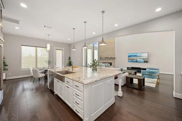 a large kitchen with stainless steel appliances kitchen island a large counter top a sink a stove and a wooden floors