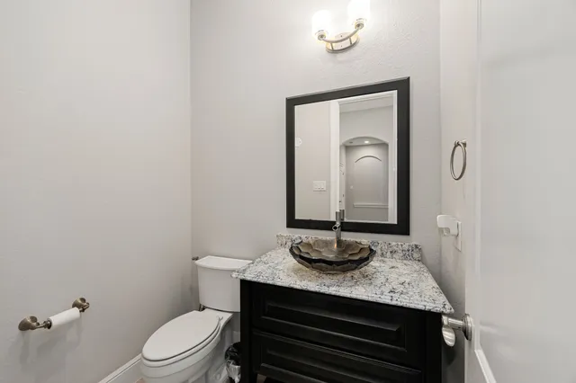 a bathroom with a granite countertop toilet sink and mirror