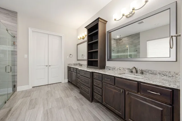 a spacious bathroom with a double vanity sink a mirror and a shower