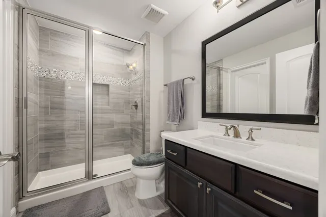 a bathroom with a shower sink vanity mirror and toilet