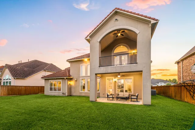 a view of a big house with a big yard and large trees