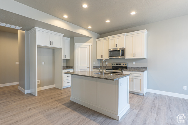 2242 South 1120 West, Unit 69 Logan, UT 84321 - Photo 7 of 26 Kitchen with dark stone counters, recessed lighting, appliances with stainless steel finishes, white cabinets, and light wood finished floors