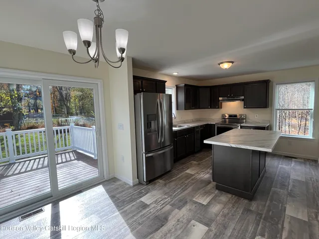 a kitchen with granite countertop a refrigerator a sink a center island a stove and cabinets