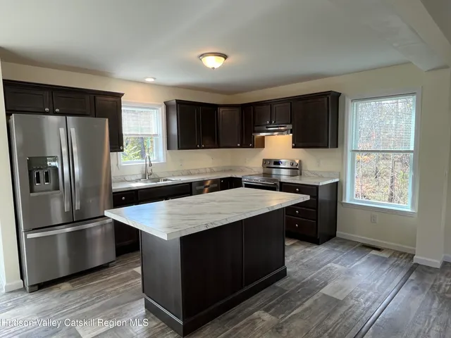 a kitchen with a refrigerator a sink dishwasher and a stove with wooden floor