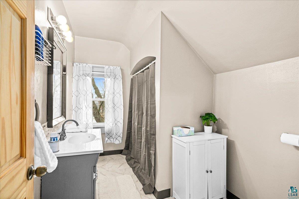 4316 West 6th Street Duluth, MN 55807 - Photo 29 of 39 Full bath featuring vanity, a shower with shower curtain, lofted ceiling, and light marble finish floors