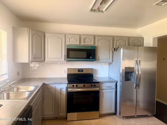 a kitchen with stainless steel appliances granite countertop a stove a refrigerator and a sink