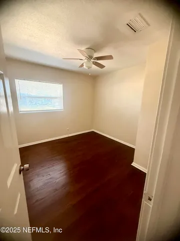 en empty room with wooden floor and fan